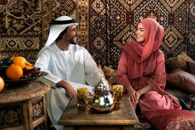 Emirati 'li genç bir çift geleneksel Arap kafesinde vakit geçiriyor. Kandura giyen kadın ve erkek Dubai 'den abaya sohbet ediyorlar..