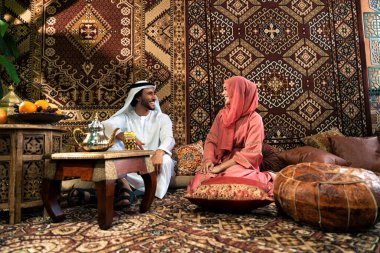 Emirati 'li genç bir çift geleneksel Arap kafesinde vakit geçiriyor. Kandura giyen kadın ve erkek Dubai 'den abaya sohbet ediyorlar..