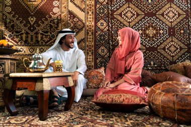 Emirati 'li genç bir çift geleneksel Arap kafesinde vakit geçiriyor. Kandura giyen kadın ve erkek Dubai 'den abaya sohbet ediyorlar..