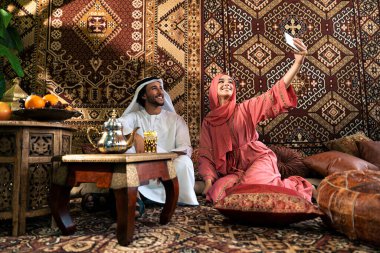 Emirati 'li genç bir çift geleneksel Arap kafesinde vakit geçiriyor. Kandura giyen kadın ve erkek Dubai 'den abaya sohbet ediyorlar..