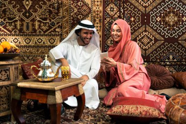 Emirati 'li genç bir çift geleneksel Arap kafesinde vakit geçiriyor. Kandura giyen kadın ve erkek Dubai 'den abaya sohbet ediyorlar..