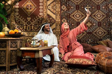 Emirati 'li genç bir çift geleneksel Arap kafesinde vakit geçiriyor. Kandura giyen kadın ve erkek Dubai 'den abaya sohbet ediyorlar..