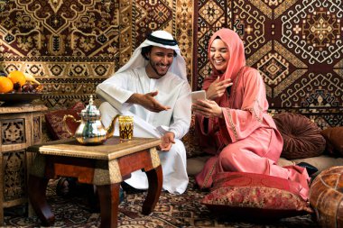 Emirati 'li genç bir çift geleneksel Arap kafesinde vakit geçiriyor. Kandura giyen kadın ve erkek Dubai 'den abaya sohbet ediyorlar..