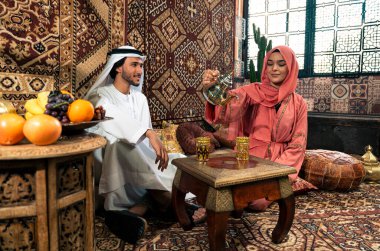 Emirati 'li genç bir çift geleneksel Arap kafesinde vakit geçiriyor. Kandura giyen kadın ve erkek Dubai 'den abaya sohbet ediyorlar..