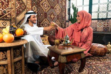 Emirati 'li genç bir çift geleneksel Arap kafesinde vakit geçiriyor. Kandura giyen kadın ve erkek Dubai 'den abaya sohbet ediyorlar..