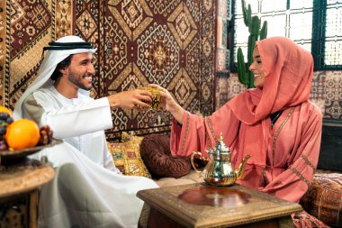 Emirati 'li genç bir çift geleneksel Arap kafesinde vakit geçiriyor. Kandura giyen kadın ve erkek Dubai 'den abaya sohbet ediyorlar..