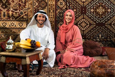 Emirati 'li genç bir çift geleneksel Arap kafesinde vakit geçiriyor. Kandura giyen kadın ve erkek Dubai 'den abaya sohbet ediyorlar..