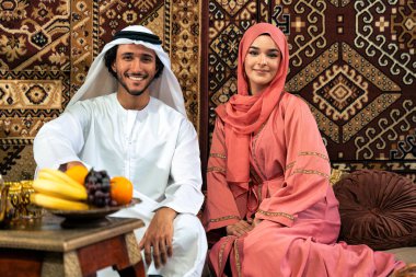 Emirati 'li genç bir çift geleneksel Arap kafesinde vakit geçiriyor. Kandura giyen kadın ve erkek Dubai 'den abaya sohbet ediyorlar..