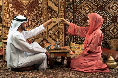 Emirati 'li genç bir çift geleneksel Arap kafesinde vakit geçiriyor. Kandura giyen kadın ve erkek Dubai 'den abaya sohbet ediyorlar..