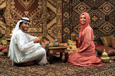 Emirati 'li genç bir çift geleneksel Arap kafesinde vakit geçiriyor. Kandura giyen kadın ve erkek Dubai 'den abaya sohbet ediyorlar..