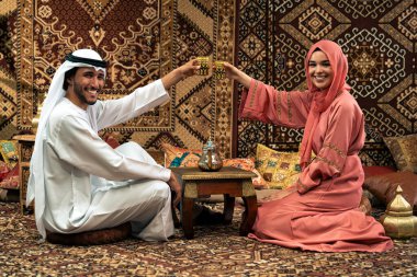 Emirati 'li genç bir çift geleneksel Arap kafesinde vakit geçiriyor. Kandura giyen kadın ve erkek Dubai 'den abaya sohbet ediyorlar..