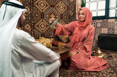 Emirati 'li genç bir çift geleneksel Arap kafesinde vakit geçiriyor. Kandura giyen kadın ve erkek Dubai 'den abaya sohbet ediyorlar..