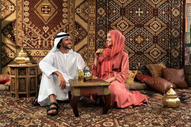 Emirati 'li genç bir çift geleneksel Arap kafesinde vakit geçiriyor. Kandura giyen kadın ve erkek Dubai 'den abaya sohbet ediyorlar..