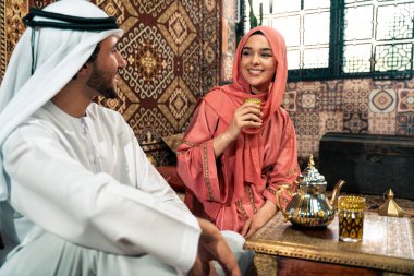 Emirati 'li genç bir çift geleneksel Arap kafesinde vakit geçiriyor. Kandura giyen kadın ve erkek Dubai 'den abaya sohbet ediyorlar..