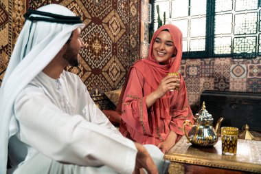 Emirati 'li genç bir çift geleneksel Arap kafesinde vakit geçiriyor. Kandura giyen kadın ve erkek Dubai 'den abaya sohbet ediyorlar..