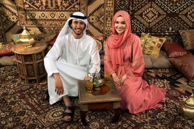 Emirati 'li genç bir çift geleneksel Arap kafesinde vakit geçiriyor. Kandura giyen kadın ve erkek Dubai 'den abaya sohbet ediyorlar..