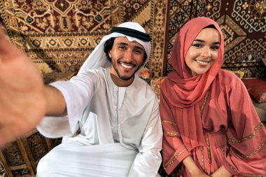 Emirati 'li genç bir çift geleneksel Arap kafesinde vakit geçiriyor. Kandura giyen kadın ve erkek Dubai 'den abaya sohbet ediyorlar..