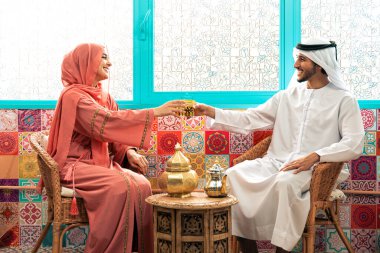 Emirati 'li genç bir çift geleneksel Arap kafesinde vakit geçiriyor. Kandura giyen kadın ve erkek Dubai 'den abaya sohbet ediyorlar..