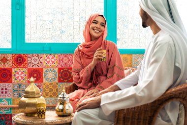 Emirati 'li genç bir çift geleneksel Arap kafesinde vakit geçiriyor. Kandura giyen kadın ve erkek Dubai 'den abaya sohbet ediyorlar..