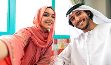 Emirati 'li genç bir çift geleneksel Arap kafesinde vakit geçiriyor. Kandura giyen kadın ve erkek Dubai 'den abaya sohbet ediyorlar..