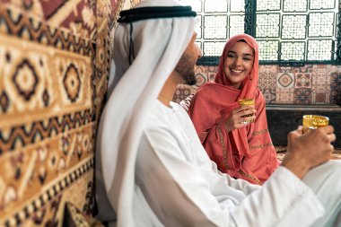 Emirati 'li genç bir çift geleneksel Arap kafesinde vakit geçiriyor. Kandura giyen kadın ve erkek Dubai 'den abaya sohbet ediyorlar..