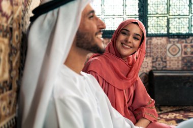 Emirati 'li genç bir çift geleneksel Arap kafesinde vakit geçiriyor. Kandura giyen kadın ve erkek Dubai 'den abaya sohbet ediyorlar..