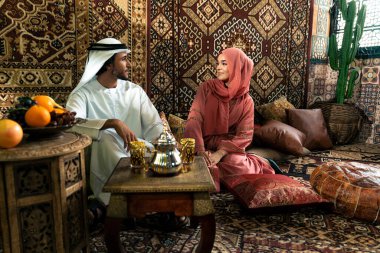 Emirati 'li genç bir çift geleneksel Arap kafesinde vakit geçiriyor. Kandura giyen kadın ve erkek Dubai 'den abaya sohbet ediyorlar..