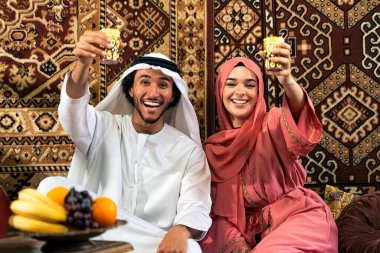 Emirati 'li genç bir çift geleneksel Arap kafesinde vakit geçiriyor. Kandura giyen kadın ve erkek Dubai 'den abaya sohbet ediyorlar..