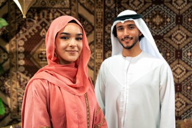 Emirati 'li genç bir çift geleneksel Arap kafesinde vakit geçiriyor. Kandura giyen kadın ve erkek Dubai 'den abaya sohbet ediyorlar..