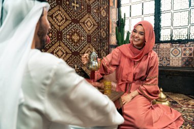 Emirati 'li genç bir çift geleneksel Arap kafesinde vakit geçiriyor. Kandura giyen kadın ve erkek Dubai 'den abaya sohbet ediyorlar..