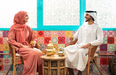 Emirati 'li genç bir çift geleneksel Arap kafesinde vakit geçiriyor. Kandura giyen kadın ve erkek Dubai 'den abaya sohbet ediyorlar..