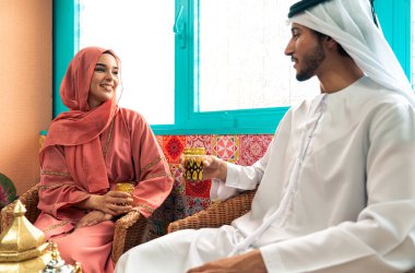 Emirati 'li genç bir çift geleneksel Arap kafesinde vakit geçiriyor. Kandura giyen kadın ve erkek Dubai 'den abaya sohbet ediyorlar..