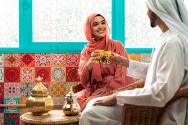 Emirati 'li genç bir çift geleneksel Arap kafesinde vakit geçiriyor. Kandura giyen kadın ve erkek Dubai 'den abaya sohbet ediyorlar..