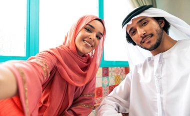 Emirati 'li genç bir çift geleneksel Arap kafesinde vakit geçiriyor. Kandura giyen kadın ve erkek Dubai 'den abaya sohbet ediyorlar..