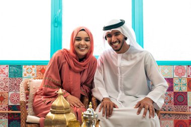 Emirati 'li genç bir çift geleneksel Arap kafesinde vakit geçiriyor. Kandura giyen kadın ve erkek Dubai 'den abaya sohbet ediyorlar..