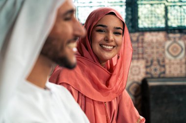 Emirati 'li genç bir çift geleneksel Arap kafesinde vakit geçiriyor. Kandura giyen kadın ve erkek Dubai 'den abaya sohbet ediyorlar..