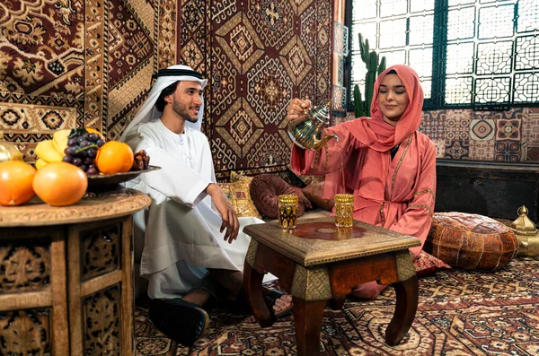 Emirati 'li genç bir çift geleneksel Arap kafesinde vakit geçiriyor. Kandura giyen kadın ve erkek Dubai 'den abaya sohbet ediyorlar..