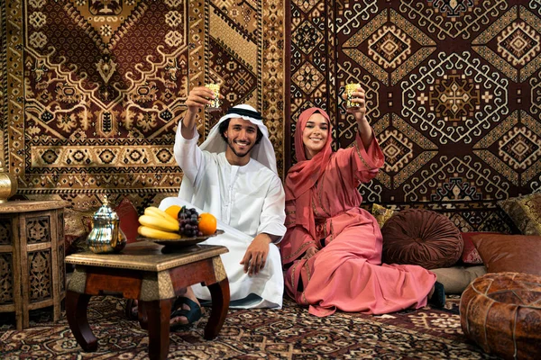 Emirati 'li genç bir çift geleneksel Arap kafesinde vakit geçiriyor. Kandura giyen kadın ve erkek Dubai 'den abaya sohbet ediyorlar..