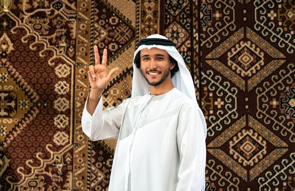 Emirati 'den kandura kıyafeti giyen bir adam Dubai' de geleneksel bir Arap evinde vakit geçiriyor.