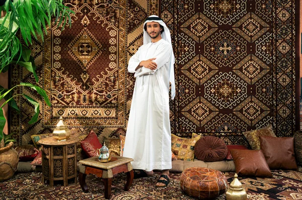 Emirati 'den kandura kıyafeti giyen bir adam Dubai' de geleneksel bir Arap evinde vakit geçiriyor.