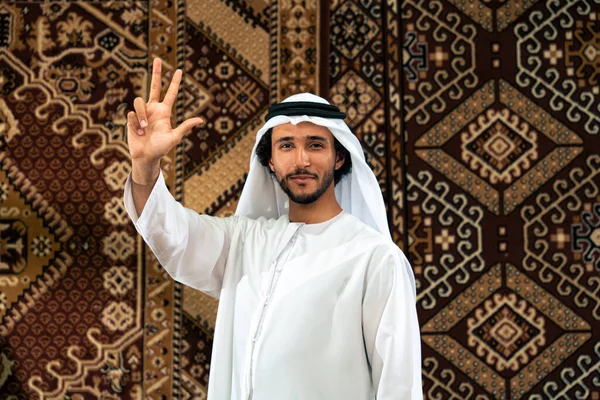 Emirati 'den kandura kıyafeti giyen bir adam Dubai' de geleneksel bir Arap evinde vakit geçiriyor.