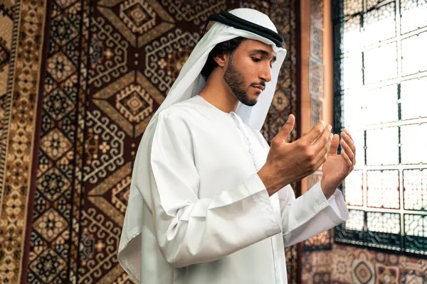 Emirati 'den kandura kıyafeti giyen bir adam Dubai' de geleneksel bir Arap evinde vakit geçiriyor.