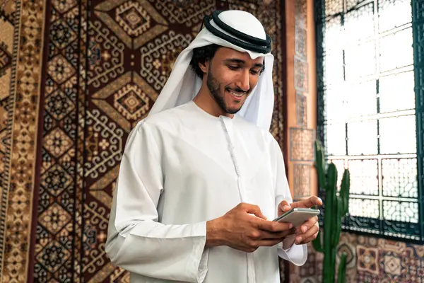 Man from emirati wearing kandura outfit spending time in an arabian traditional house in Dubai