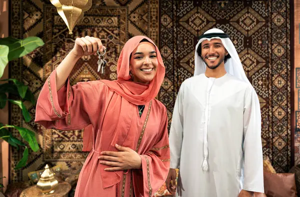 Young couple from Emirati spending time in an arabian traditional cafe. Man and woman wearing kandura and abaya from Dubai conversating together.