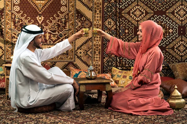 Emirati 'li genç bir çift geleneksel Arap kafesinde vakit geçiriyor. Kandura giyen kadın ve erkek Dubai 'den abaya sohbet ediyorlar..