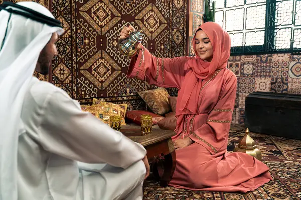 Emirati 'li genç bir çift geleneksel Arap kafesinde vakit geçiriyor. Kandura giyen kadın ve erkek Dubai 'den abaya sohbet ediyorlar..