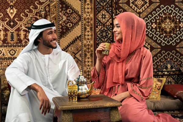 Emirati 'li genç bir çift geleneksel Arap kafesinde vakit geçiriyor. Kandura giyen kadın ve erkek Dubai 'den abaya sohbet ediyorlar..