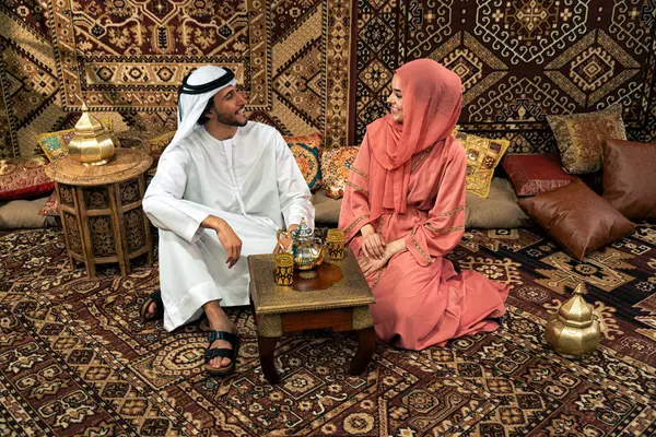 Emirati 'li genç bir çift geleneksel Arap kafesinde vakit geçiriyor. Kandura giyen kadın ve erkek Dubai 'den abaya sohbet ediyorlar..