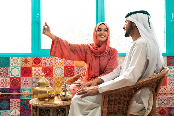 Emirati 'li genç bir çift geleneksel Arap kafesinde vakit geçiriyor. Kandura giyen kadın ve erkek Dubai 'den abaya sohbet ediyorlar..