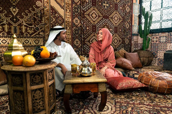 Emirati 'li genç bir çift geleneksel Arap kafesinde vakit geçiriyor. Kandura giyen kadın ve erkek Dubai 'den abaya sohbet ediyorlar..